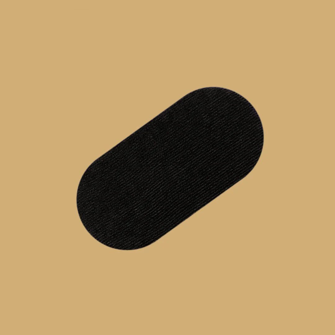 En enkel, oval REZT munntape i svart, sentrert på en varm beige bakgrunn. Tapen er flatt presentert og teksturen ser myk og behagelig ut, designet for å være komfortabel å bruke mens man sover
